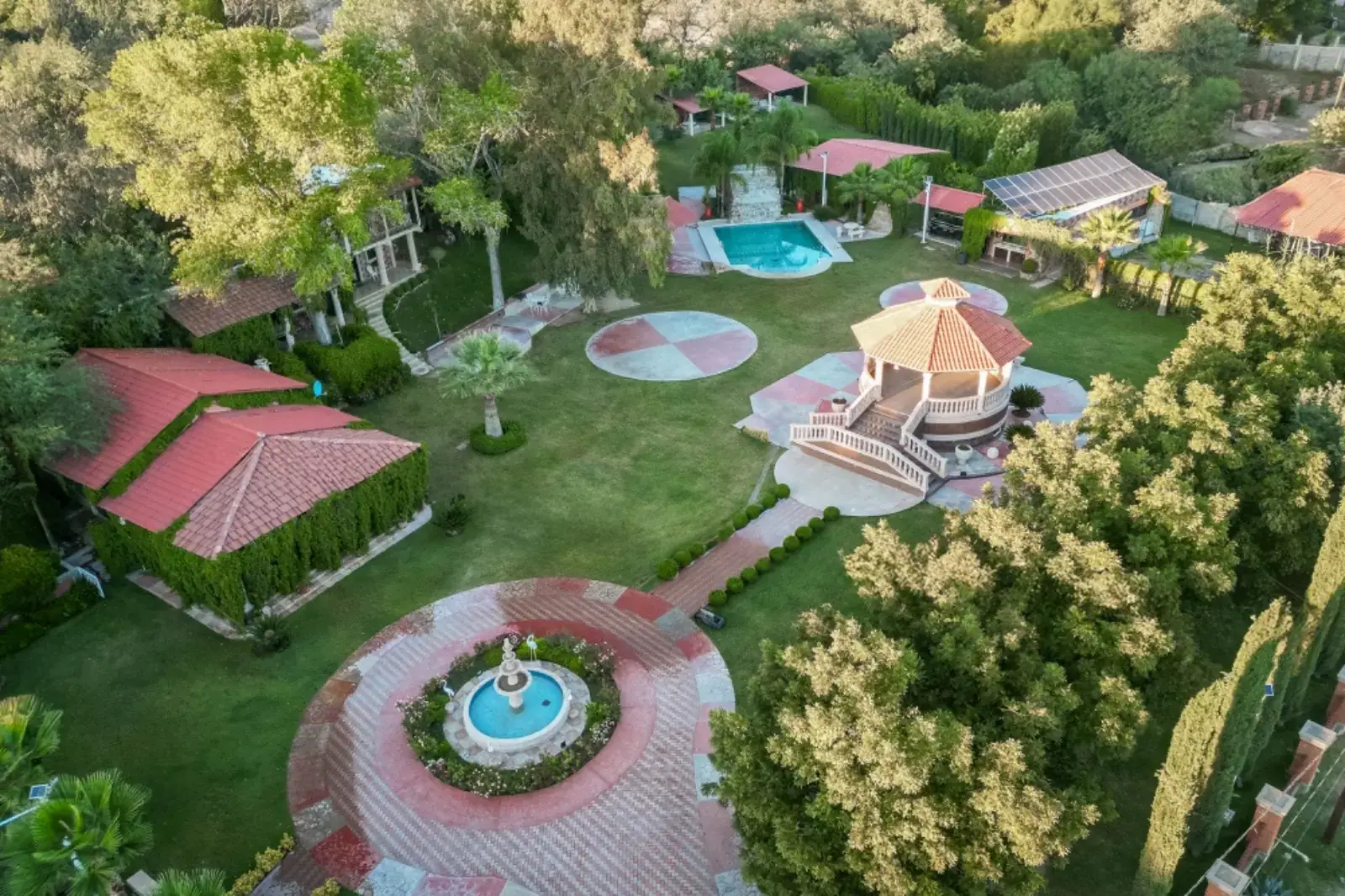 Vista aérea de los jardines con la fuente, el kiosko y la alberca entre árboles