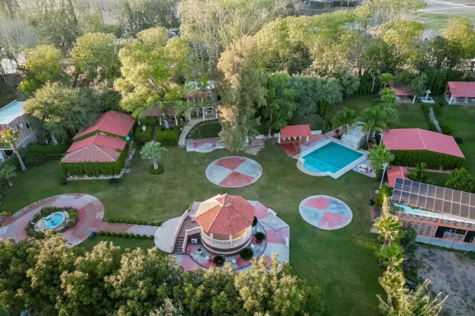 Vista aérea de la alberca, el kiosko y las casas de techo de teja entre jardines
